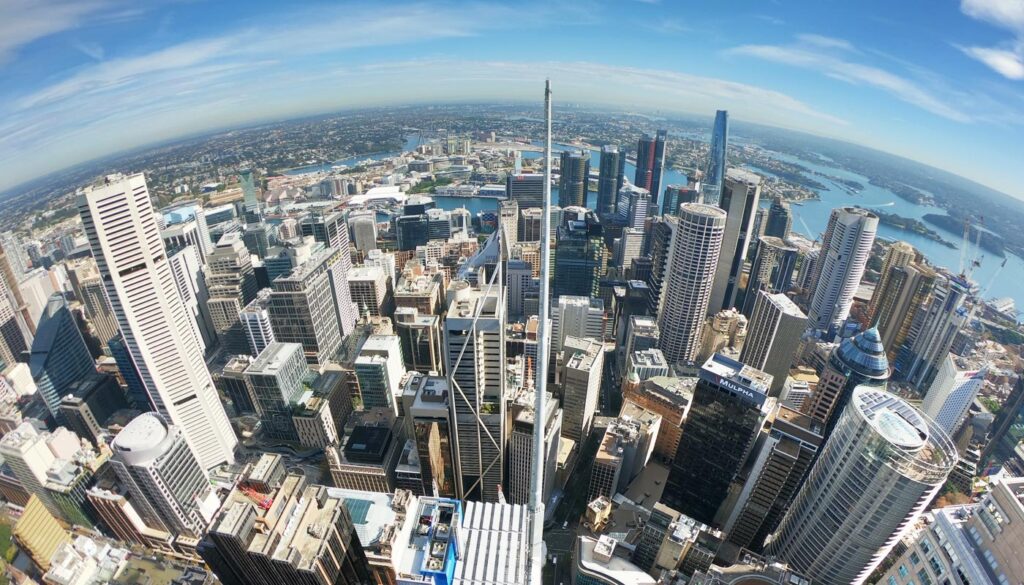 Aerial fisheye view of a dense cityscape with skyscrapers and waterfront.