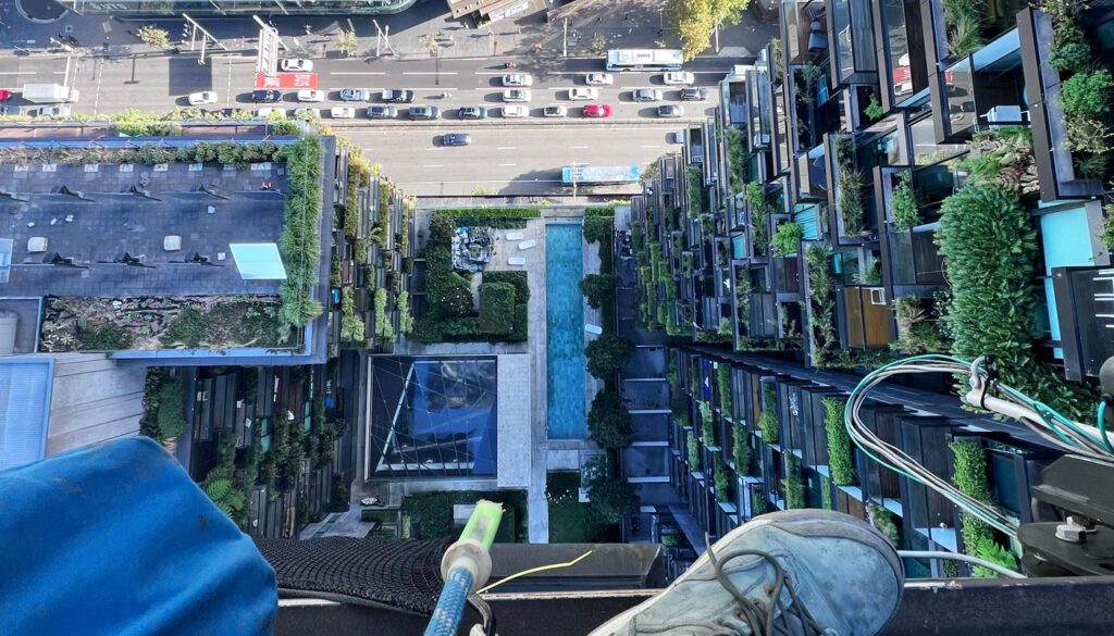 High-angle view from a building overlooking a city street and a courtyard with greenery and water features.