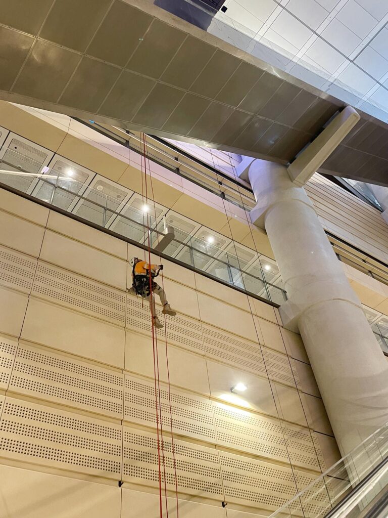 A window washer rappels down the side of a multi-story building.